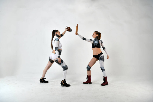 two beautiful girls in suits of robots as children fight fighting weapons and improvised means - Photo, Image