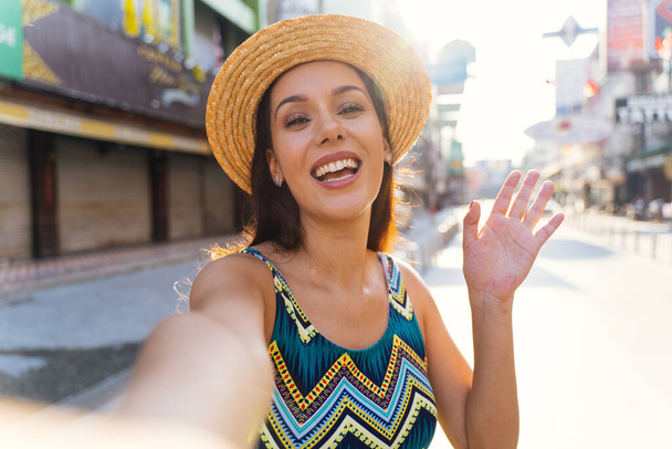 Young brunette woman using a mobile phone takes a self video selfie with attractive smile. - Photo, image