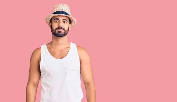 Young hispanic man wearing casual summer hat relaxed with serious expression on face. simple and natural looking at the camera.  - Foto, immagini