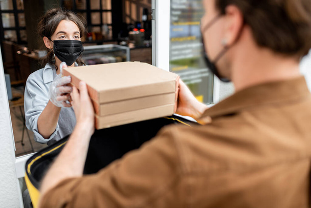 Kurier nimmt Bestellung für Lieferung aus dem Schaufenster entgegen - Foto, Bild