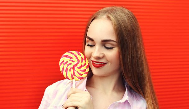 Portrait girl with lollipop on a red wall background - Fotó, kép