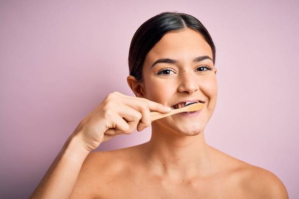 Junge schöne brünette Frau putzt ihre Zähne mit Zahnbürste und Oralpasta, Zähne und Zunge putzen als gesunde Gesundheitspflege Morgenroutine - Foto, Bild