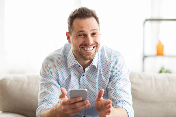 Opgewonden volwassen man die zich extatisch voelt terwijl hij mobiele telefoon vasthoudt - Foto, afbeelding