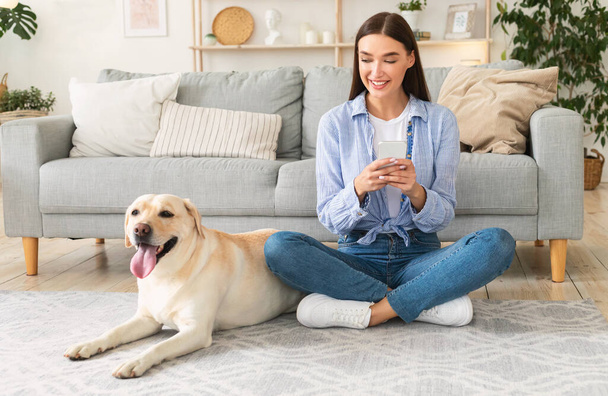 Portrait of young woman with her dog using mobile phone - Foto, Imagen