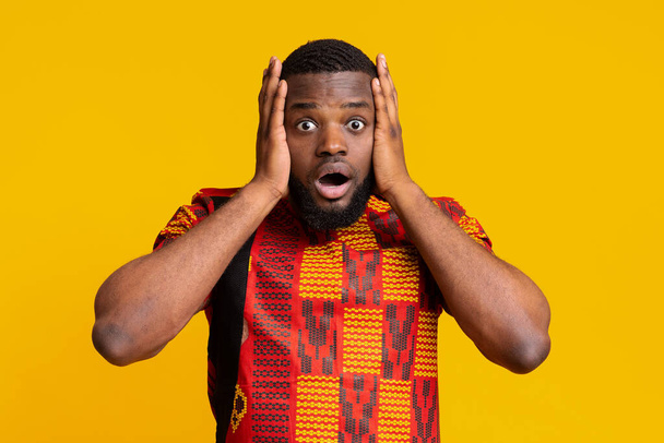 Shocked african guy with open mouth holding his head - Fotó, kép
