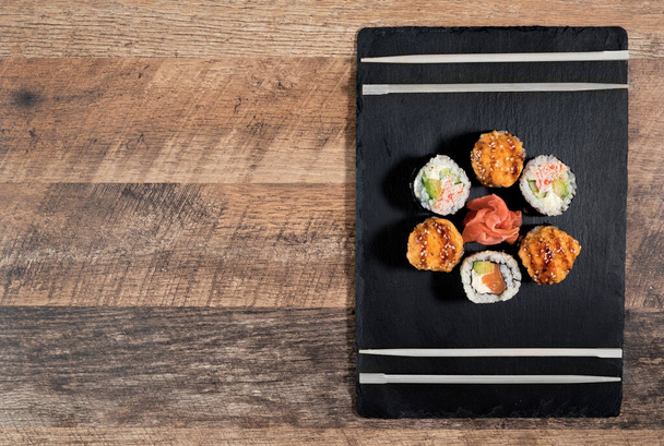 Sushi-Rollen-Set auf dem schwarzen Teller. Japanisches Essen. - Foto, Bild