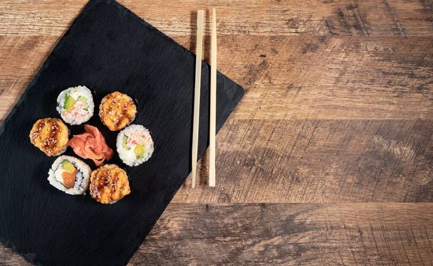 Суши-булочки на черной тарелке. Японская кухня
. - Фото, изображение