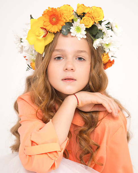Studio foto van een mooi langharig roodharig meisje met chique krullen, witte achtergrond. Een bosnimf met een bloemaccessoire op het hoofd. Reclame kappersproducten in sociale netwerken, website - Foto, afbeelding