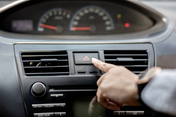 Woman use finger press emergency button on car console for turn on the Emergency light to warning car accident on the road,Emergency Car Concept - Fotó, kép