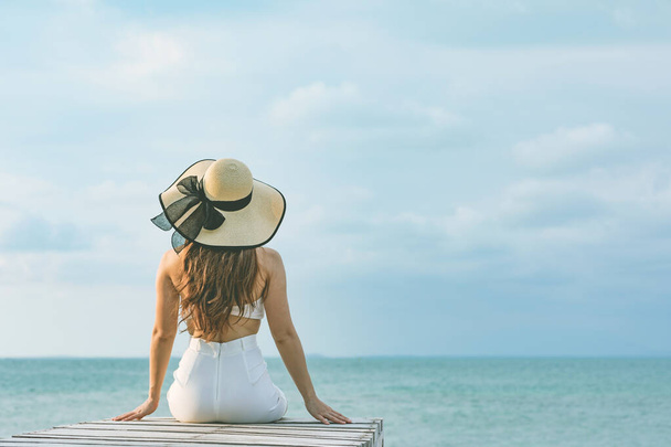Back of views young woman wearing white dress smile enjoy with summer vacation on pier on beach feeling so happiness and cheerful,Travel in tropical beach in Thailand,vacations and relaxation Concept - Foto, Imagem