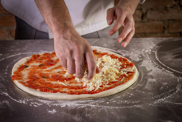 Pizza dough being prepared with tomato sauce and mozzarella. The process of making pizza - Foto, afbeelding