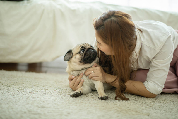 Beautiful Attractive Asian woman kissing her Cute dog pug breed with boring and funny face on bed feeling so sweet and lovely,Friendly Concept - Φωτογραφία, εικόνα