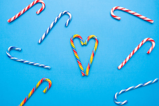 lote de bastões de doces multi-coloridos e um coração em um fundo azul, espaço de cópia
 - Foto, Imagem