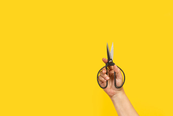 Kobieta trzyma nożyczki na żółtym tle z przestrzenią do kopiowania - Zdjęcie, obraz