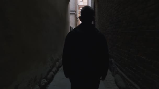 Un bel homme marche dans un tunnel entre des maisons de la vieille ville - Séquence, vidéo