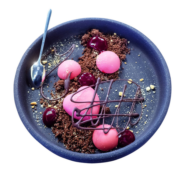 Sobremesa na forma de um coração e bolas redondas em esmalte rosa com geléia de framboesa e figura de chocolate em um biscoito desintegrado em uma placa cerâmica. Fundo isolado
 - Foto, Imagem