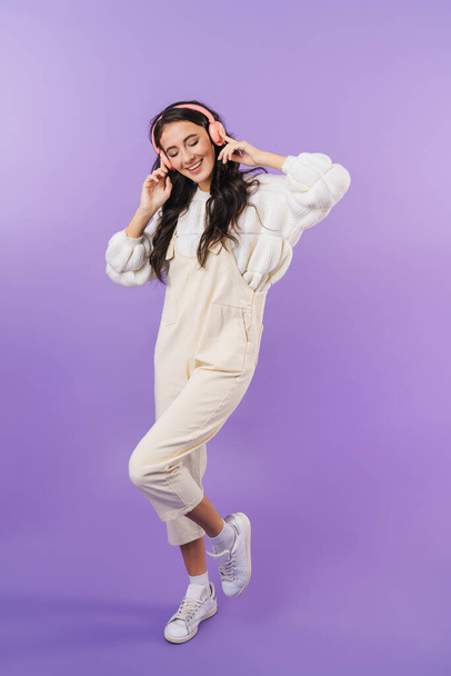 Photo of happy cheery brunette woman posing isolated over purple wall background listening music with headphones. - Foto, Imagem
