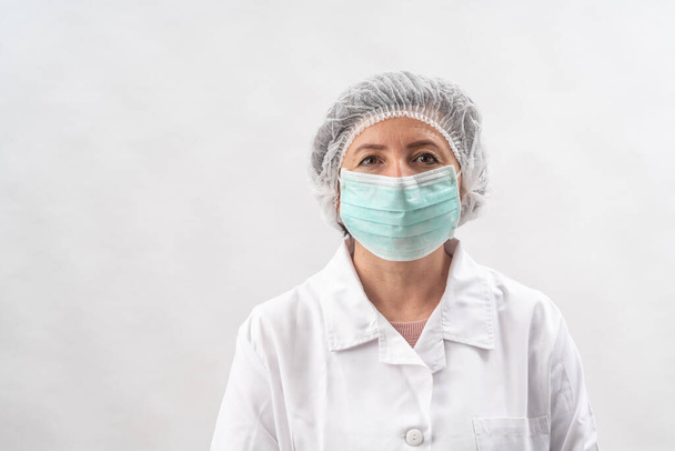Tired female medic, nurse in protective equipment and a mask from viruses, on a white background. - Foto, immagini