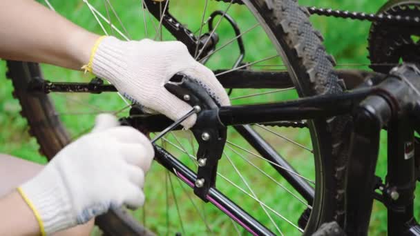 Mężczyzna w rękawiczkach naprawia kroki rowerowe. Konserwacja roweru górskiego w miejscu naprawy specjalisty zbliżenie. Naprawa pojazdu letniego, aktywny tryb życia. - Materiał filmowy, wideo