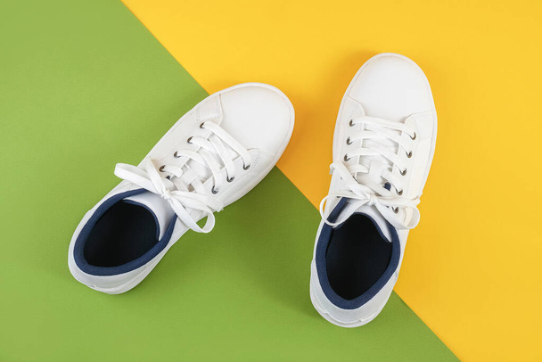 White sports shoes, sneakers with shoelaces on a green and yellow background. Sport lifestyle concept Top view Flat lay. - Фото, зображення