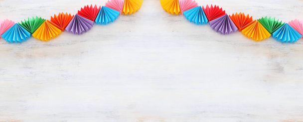 Paper colorful chain garland over white wooden background. Traditional jewish sukkot holiday decoration - Photo, Image