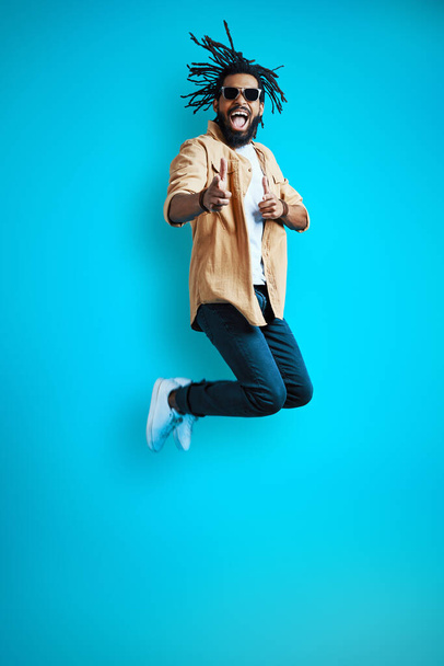 Full length of cheerful Young African man in casual wear shouting and gesturing while hovering against blue background - Fotografie, Obrázek