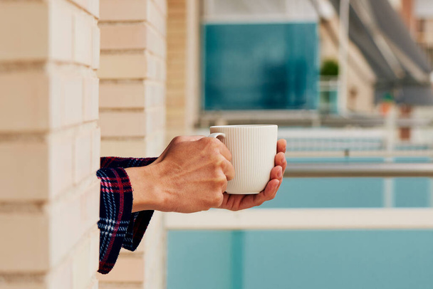 крупним планом молодий кавказький чоловік, у піжамі, має каву, що спирається на підвіконня вікна, в його будинку або готелі
 - Фото, зображення