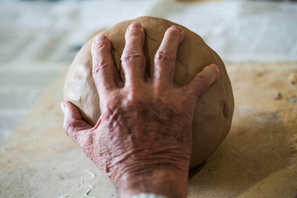 une main touchant une boule d'argile, une perception tactile et haptique humaine - Photo, image