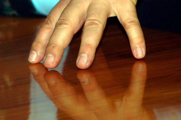 een hand die houten reflecterende vloer, menselijke tastbare en haptische waarneming aanraakt - Foto, afbeelding