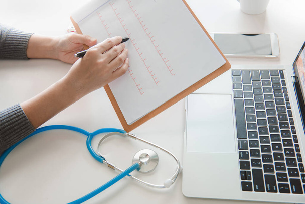 Medizintechnikkonzept. Arzt arbeitet mit Handy und Stethoskop und digitalem Tablet-Laptop in modernem Büro im Krankenhaus. - Foto, Bild