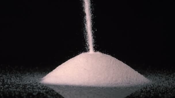 Nalanie białego cukru na czarne tło w zwolnionym tempie przy 180fps. - Materiał filmowy, wideo