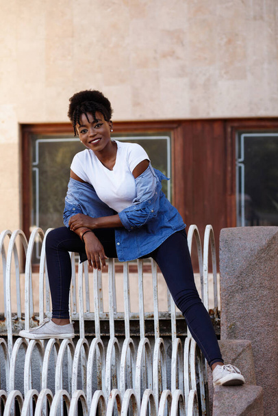 Una chica negra se sienta en los escalones de la ciudad. Igualdad
 - Foto, imagen