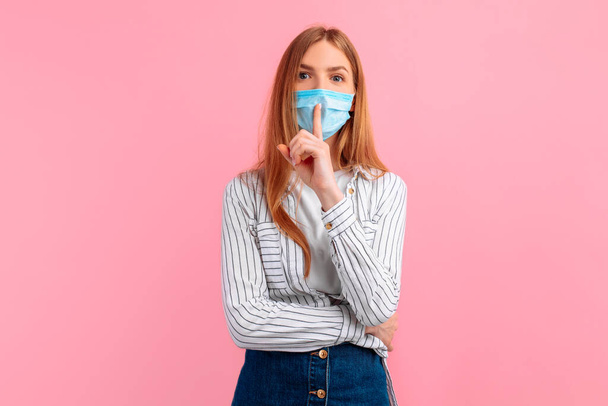 pensive young woman in a medical protective mask on her face, on an isolated pink background. Coronavirus epidemic, quarantine - Foto, Bild