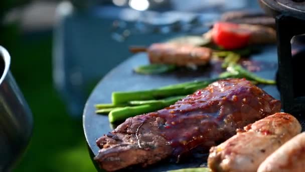 Cucini in guanti di nitrile neri spruzza la salsa su una carne di barbecue, un manzo in fuoco, una carne di maiale per una cena festiva, uno spuntino per cena - Filmati, video