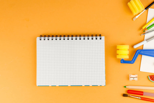 Notebook se školními potřebami na oranžovém podstavci - Fotografie, Obrázek