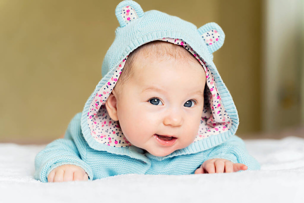 a beautiful newborn blue eyed girl lies on her tummy and smiles. - Foto, imagen
