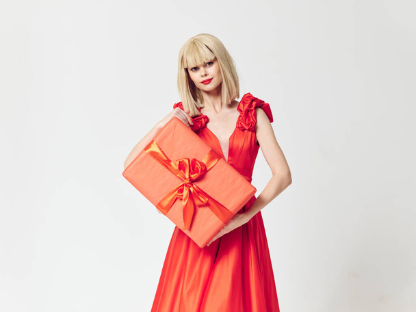 Woman in a red dress with a gift box in her hands on an isolated background - Foto, Imagem