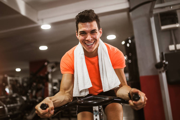 Young man doing exercise on elliptical cross trainer in sport fitness gym club - Photo, Image