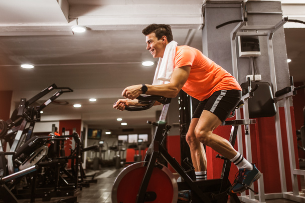 Jeune homme faisant de l'exercice sur vélo elliptique dans le club de gym de fitness sportif
 - Photo, image