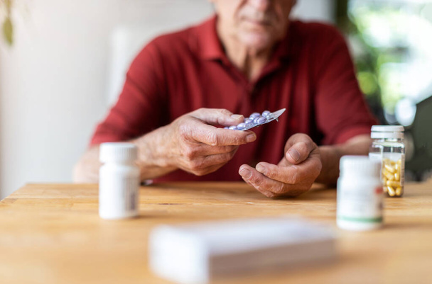 Senior man taking prescription medicine at home - Foto, afbeelding