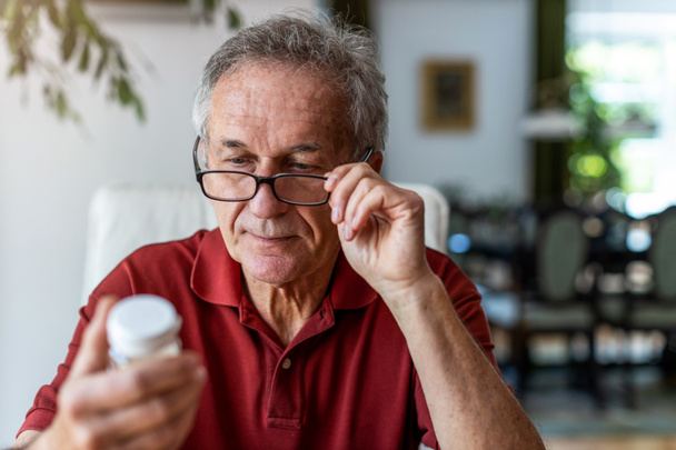 Senior man taking prescription medicine at home - Foto, Bild