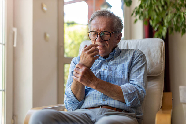 Старший чоловік з артритом натирає руки
 - Фото, зображення