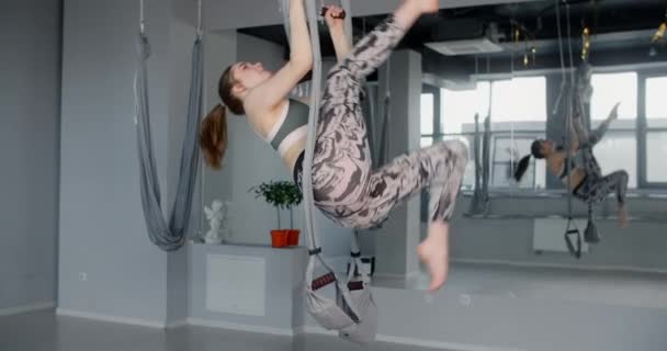 Kobieta podnosi ćwiczenia na hamaku w klasie jogi muchy, elastyczna kobieta robi gimnastykę akrobatyczną i plastyczną, jogę i rozciąganie, 4k 60p Prores 422 10 bit - Materiał filmowy, wideo