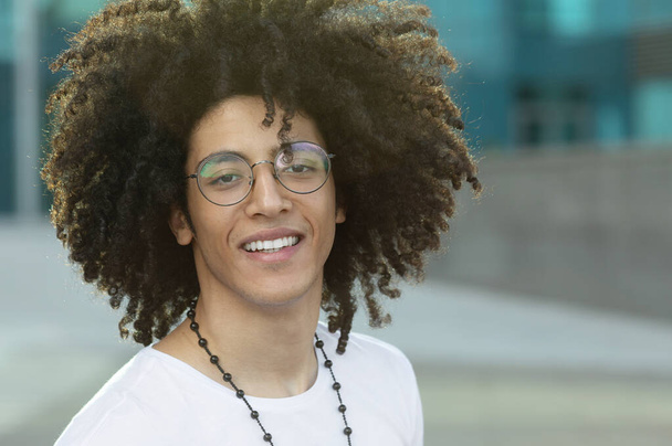 Close up portrait of handsome young black man with curly hair smiling outside. - Fotó, kép