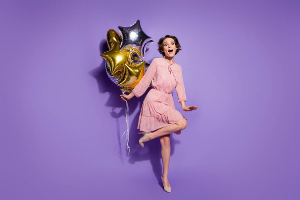 Full size photo of astonished funky girl hold star shape air balloons impressed festive holiday scream wow omg wear pastel outfit shoes isolated over violet color background - Photo, image