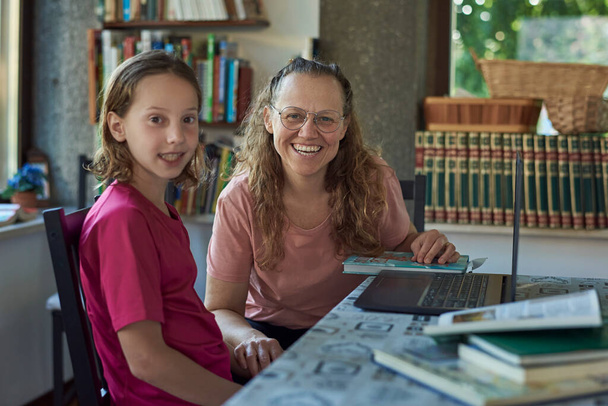Madre e hija frente a la computadora portátil estudiando en línea
 - Foto, Imagen