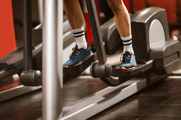 Man's legs in sneakers working on the stepper simulator in the gym - Fotó, kép