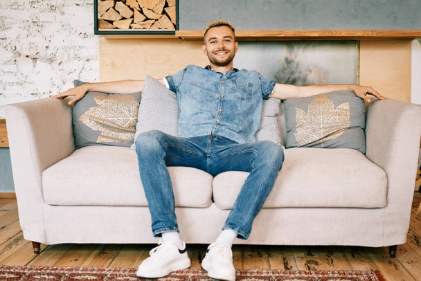 Handsome smiling man relax on sofa at home - Foto, imagen