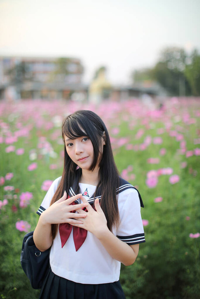 Retrato de uniforme de niña de escuela japonesa con flor de cosmos rosa  - Foto, imagen