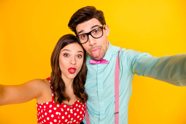 Closeup photo two people attractive lady handsome guy couple making selfies sticking tongue out mouth wear red dress shirt bowtie retro clothes isolated yellow bright color background - Photo, image